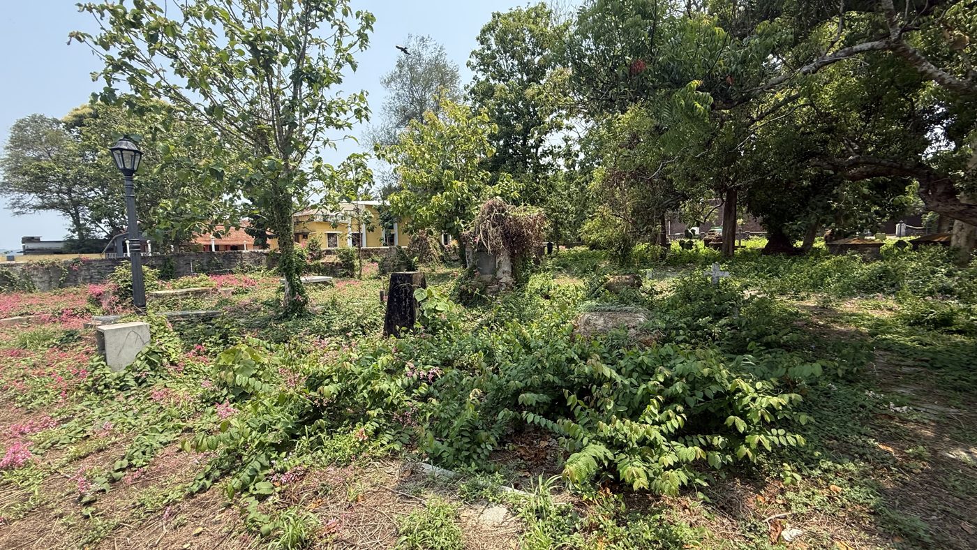 Wide view of Thalassery Anglican cemetery showing tombs and church
